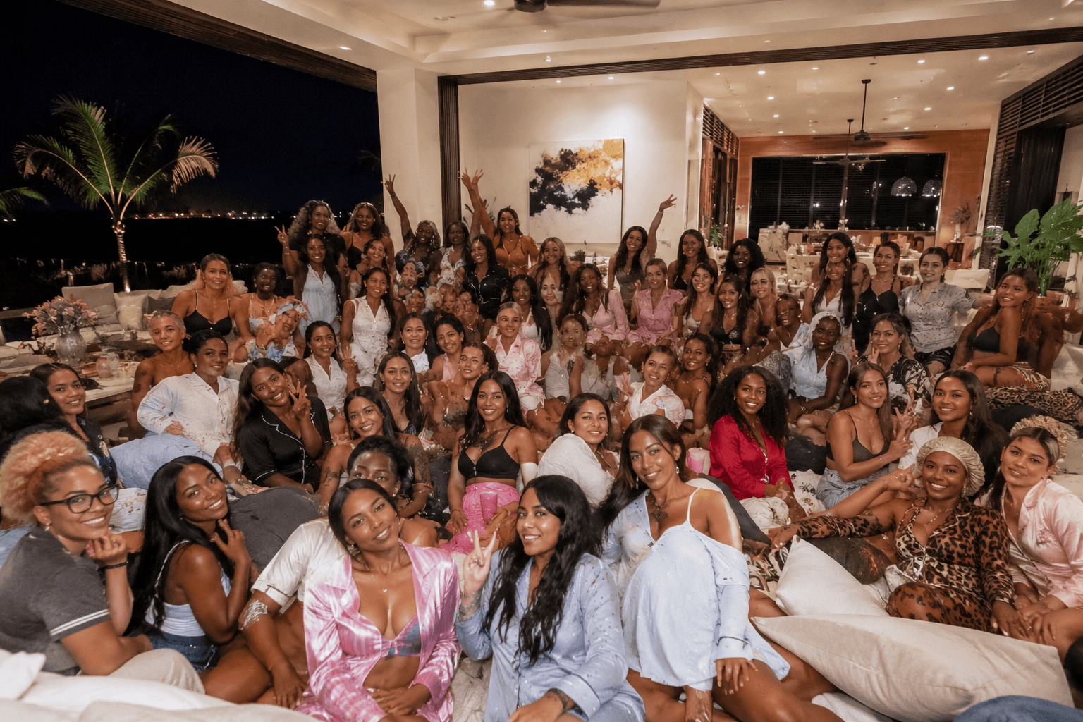 Diverse women in pajamas and loungewear posing for a group photo in a luxury villa.