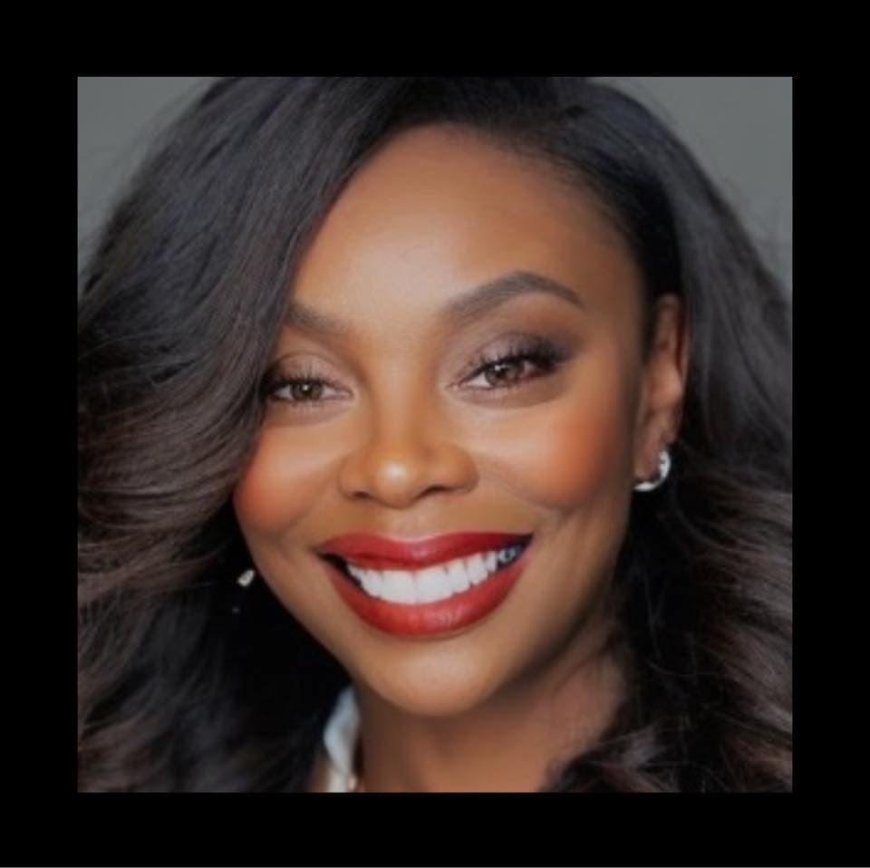 Smiling Black woman with long wavy dark hair, brown eyes, and bold red lipstick.